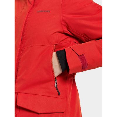 En kvinde iført en mellemlang varm parka med en justerbar hætte og flere lommer. Parkaen er beskyttende mod vind og vand og har en bæredygtig farvningsteknik.